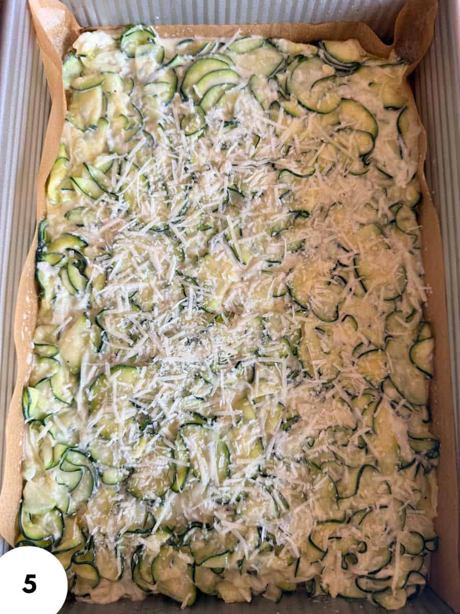Unbaked zucchini focaccia with cheese in a baking tray.