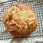 Golden round bread cooling on a wire rack, ideal for bread stretching and folding.