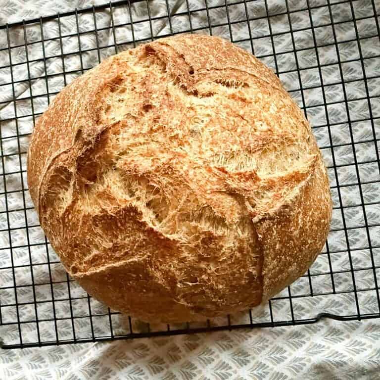Golden round bread cooling on a wire rack, ideal for bread stretching and folding.