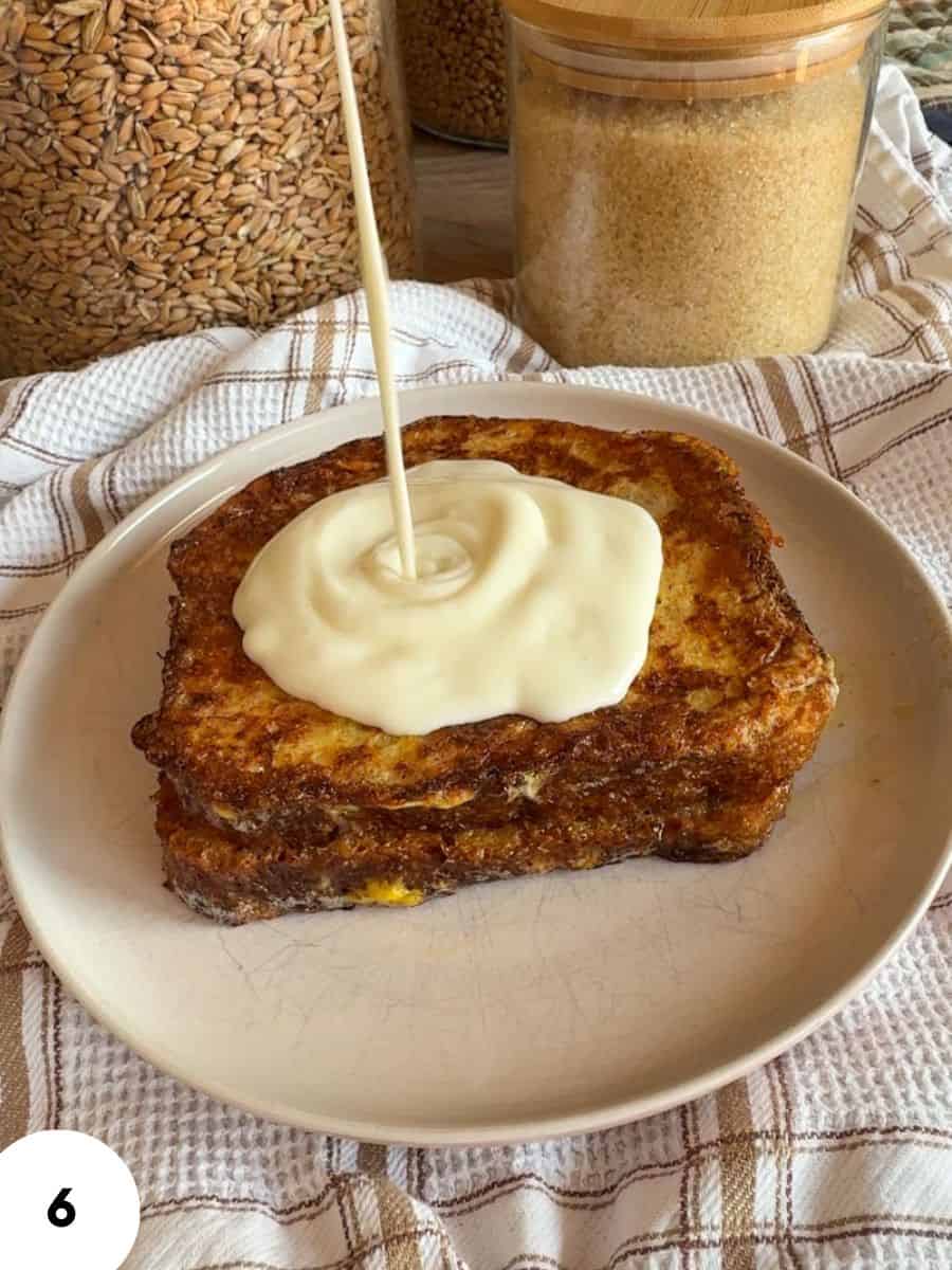 French toast topped with cream and syrup, served on a white plate.