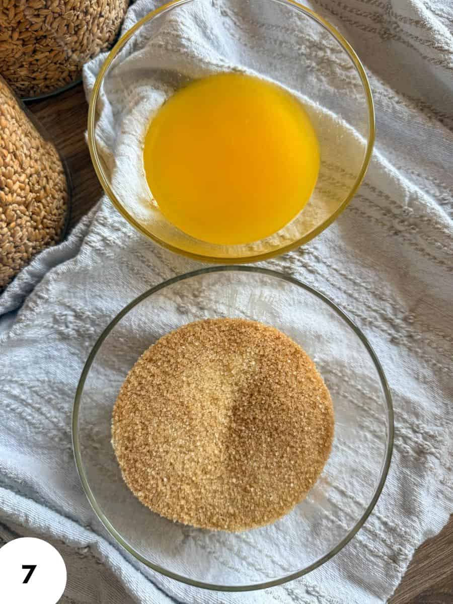 Egg wash and breadcrumbs in glass bowls for breading or baking.
