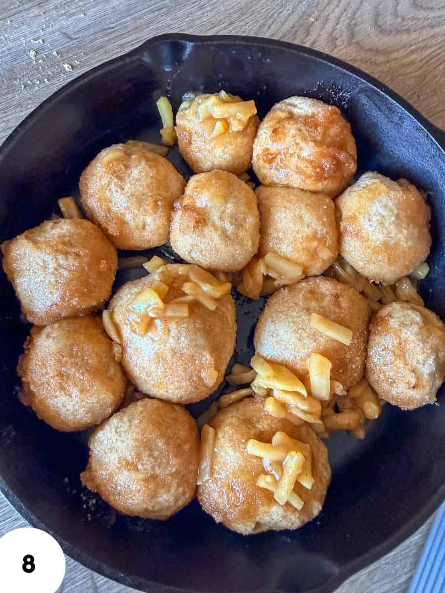 Golden fried cheese balls served in a black bowl with cheese toppings.