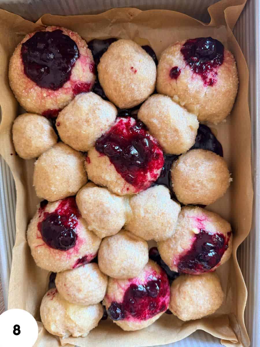 Assorted berry-filled donuts with powdered sugar and fruit topping.