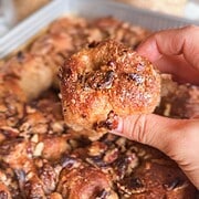 Close-up of a hand holding a sticky pecan pie pull-apart sourdough piece.