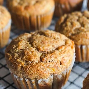 Close-up of homemade muffins with golden-brown tops on a cooling rack.