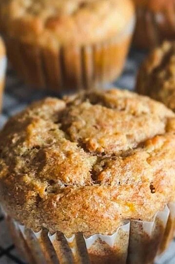 Close-up of homemade muffins with golden-brown tops on a cooling rack.