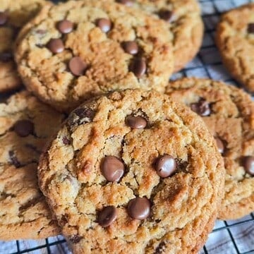 Freshly baked chocolate chip cookies with gooey chocolate chips on cooling rack.