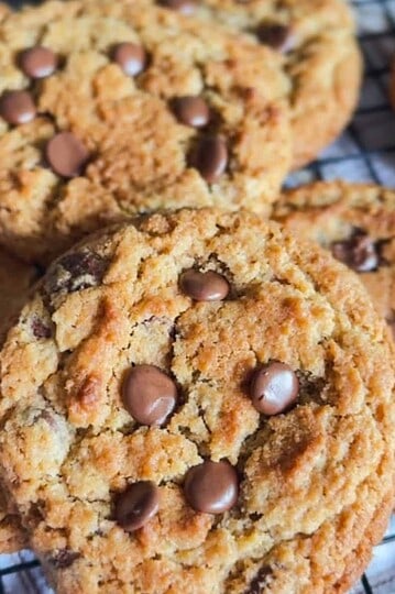 Freshly baked chocolate chip cookies with gooey chocolate chips on cooling rack.