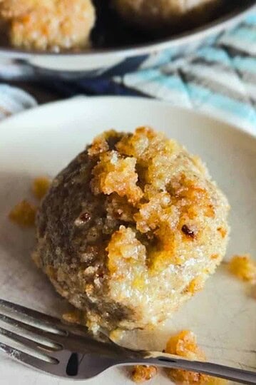 Close-up of a bread roll with crumb topping on a white plate.