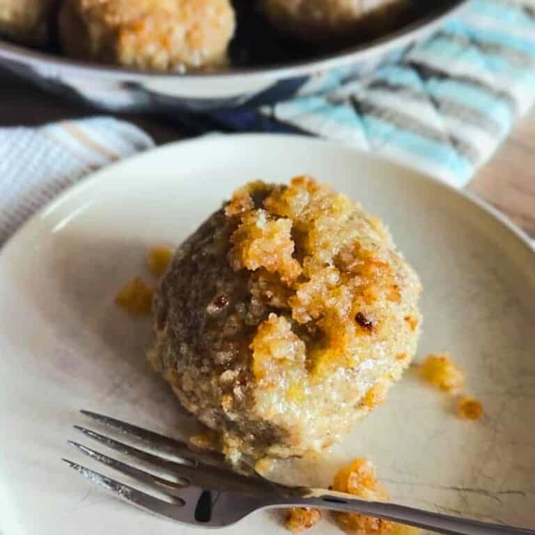 Close-up of a bread roll with crumb topping on a white plate.