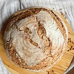 Freshly baked sourdough bread with scoring on top, on a wooden board.