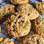 Freshly baked chocolate chip cookies on a cooling rack.