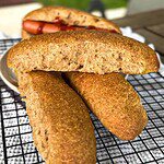 Golden brown cornbread fritters on a cooling rack with a sandwich in the background.