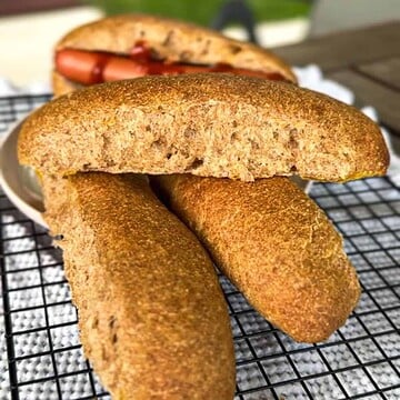 Golden brown cornbread fritters on a cooling rack with a sandwich in the background.