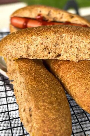 Golden brown cornbread fritters on a cooling rack with a sandwich in the background.
