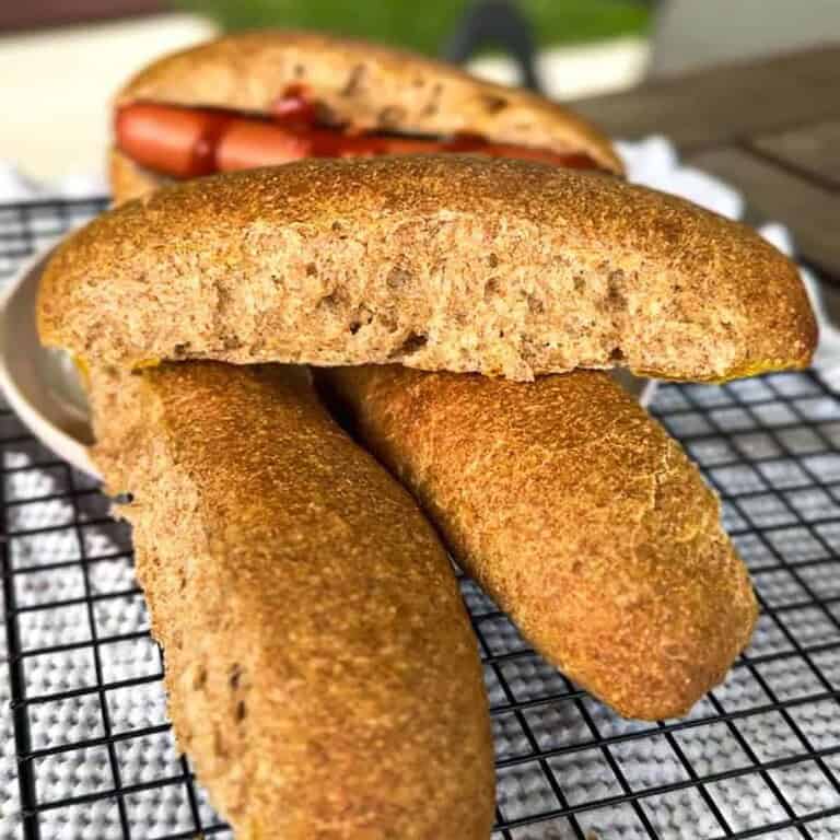 Golden brown cornbread fritters on a cooling rack with a sandwich in the background.