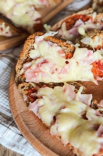 Close-up of cheesy ham bagel bites with melted cheese and ham slices.