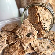 Seed crackers in a jar with scattered crackers on a plate.