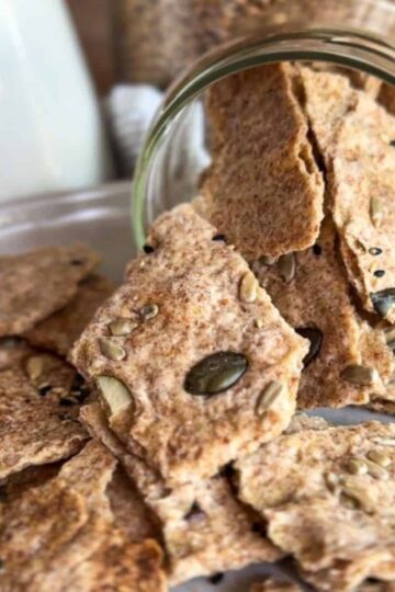 Seed crackers in a jar with scattered crackers on a plate.