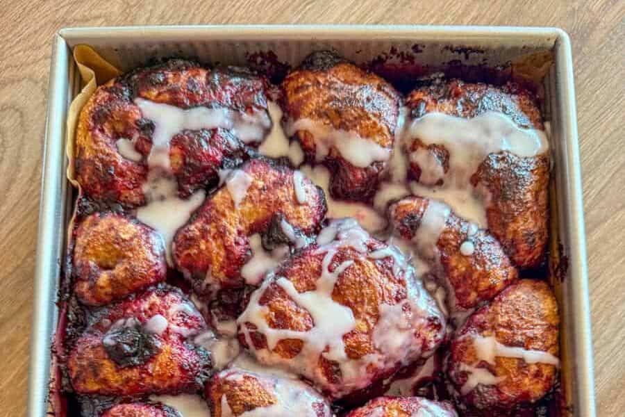 Close-up of cinnamon rolls with icing in a baking tray.