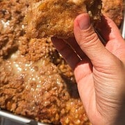 Close-up of a hand holding a slice of freshly baked bread with a crispy crust.