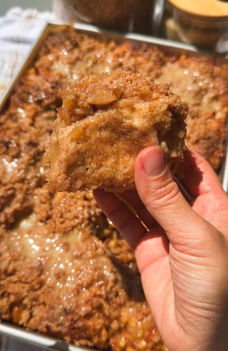 Close-up of a hand holding a slice of freshly baked bread with a crispy crust.
