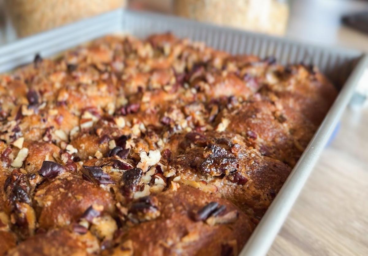 Close-up of sticky pecan pie pull-apart sourdough focaccia in a baking dish.