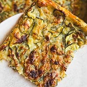 Close-up of a vegetable frittata slice with cheese and herbs.