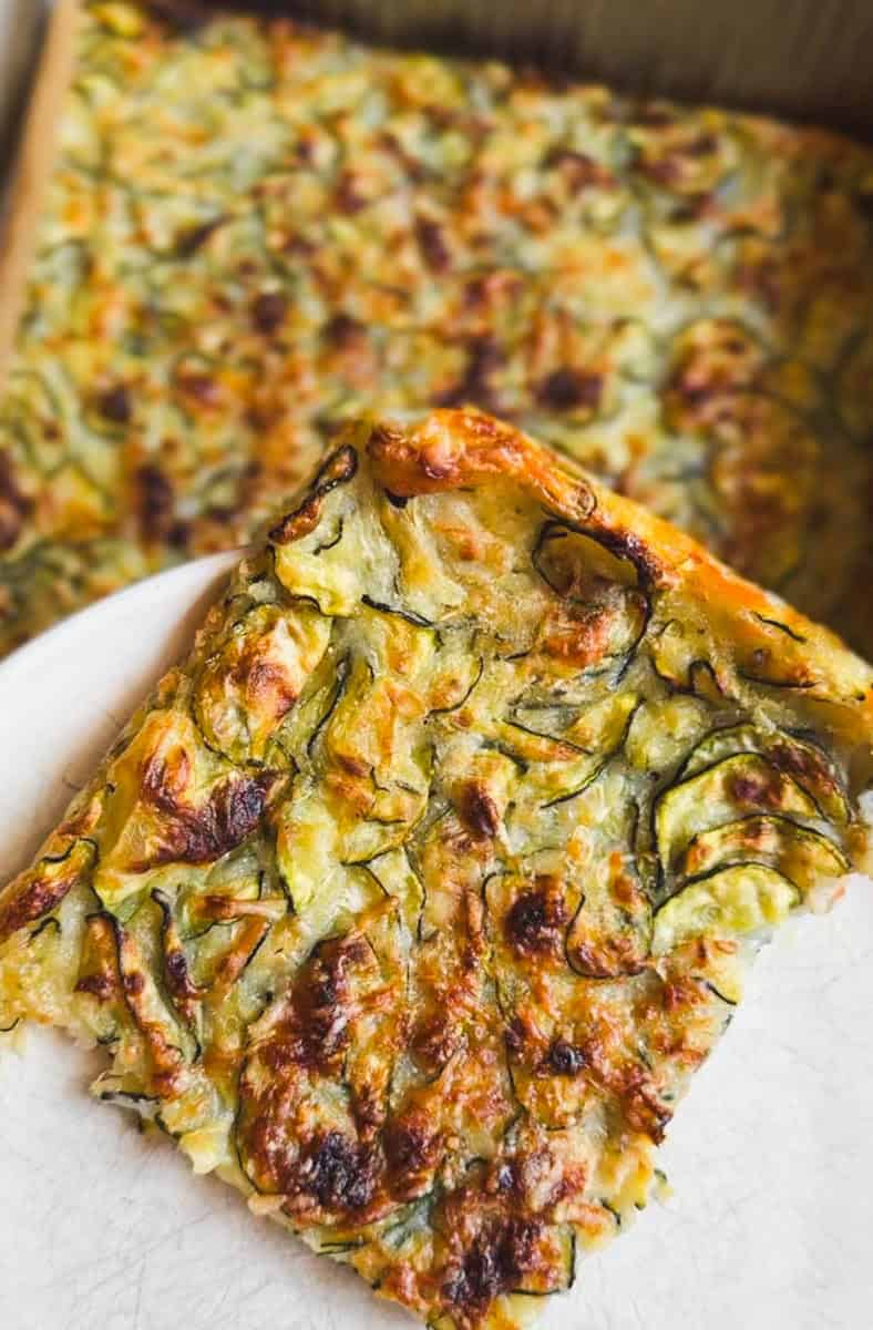 Close-up of a vegetable frittata slice with cheese and herbs.