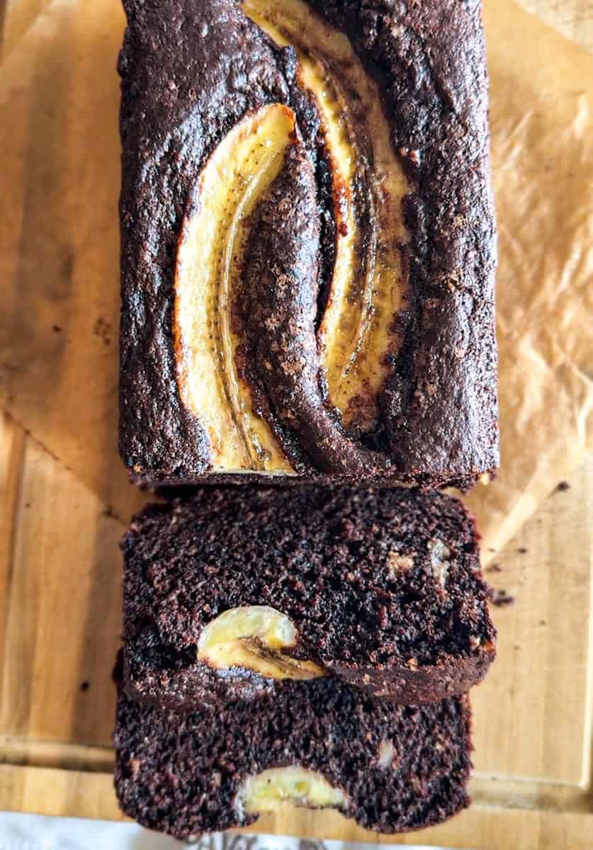 Close-up of chocolate banana bread with banana slices and swirled chocolate.