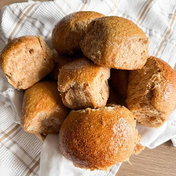 Freshly baked bread rolls on a white cloth.
