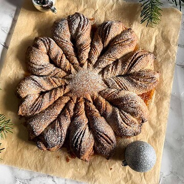 Star-shaped pastry dusted with powdered sugar on parchment paper.