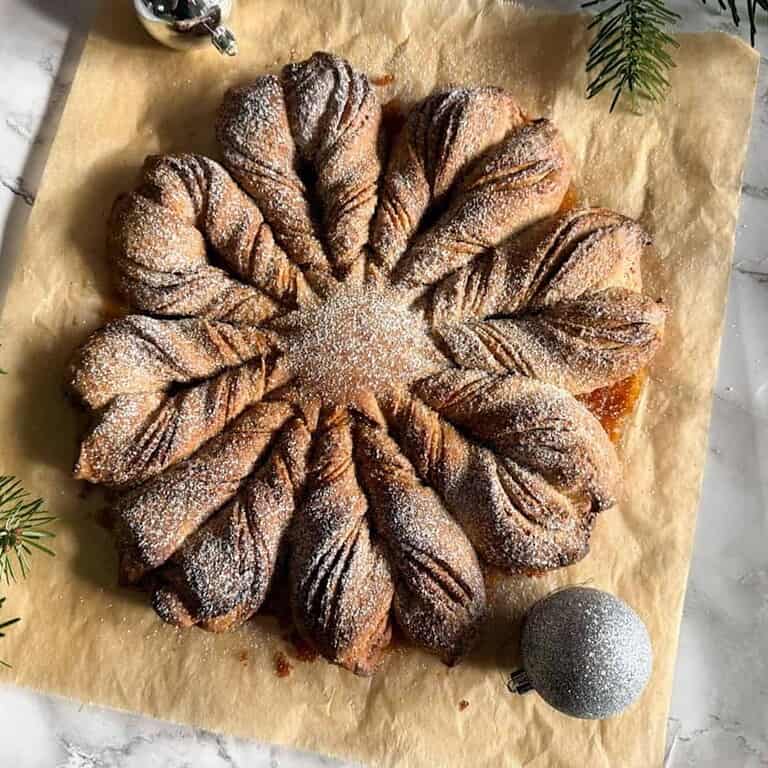 Star-shaped pastry dusted with powdered sugar on parchment paper.