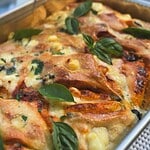 Close-up of sourdough focaccia with tomatoes, pesto, olives, and basil.