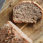 Freshly baked whole wheat bread sliced on a wooden cutting board.