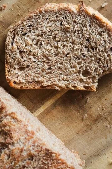 Freshly baked whole wheat bread sliced on a wooden cutting board.