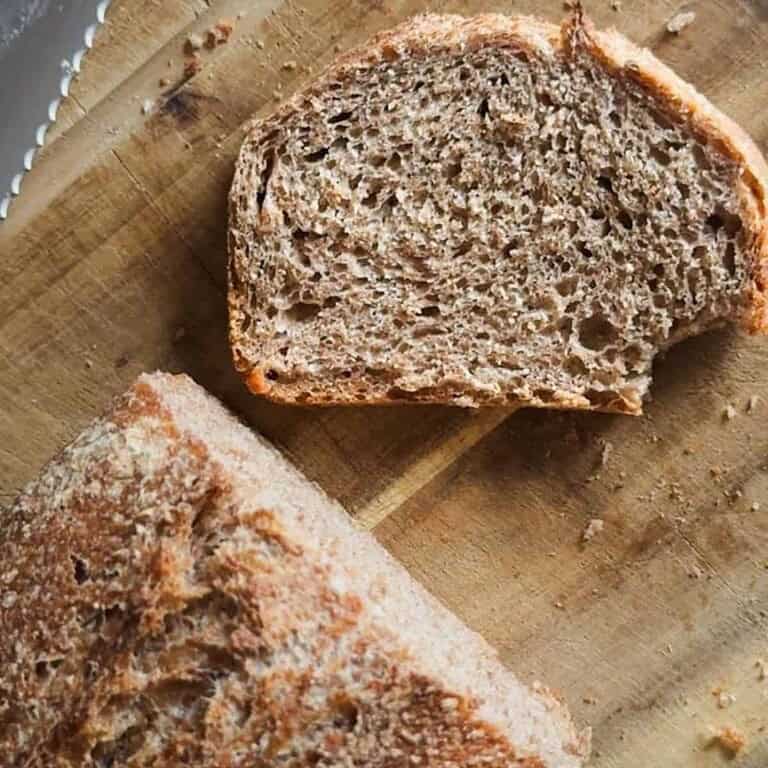 Freshly baked whole wheat bread sliced on a wooden cutting board.