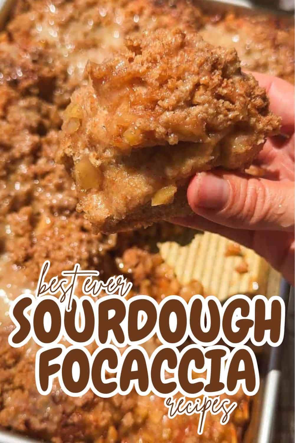 Close-up of a hand holding a piece of sourdough focaccia bread.