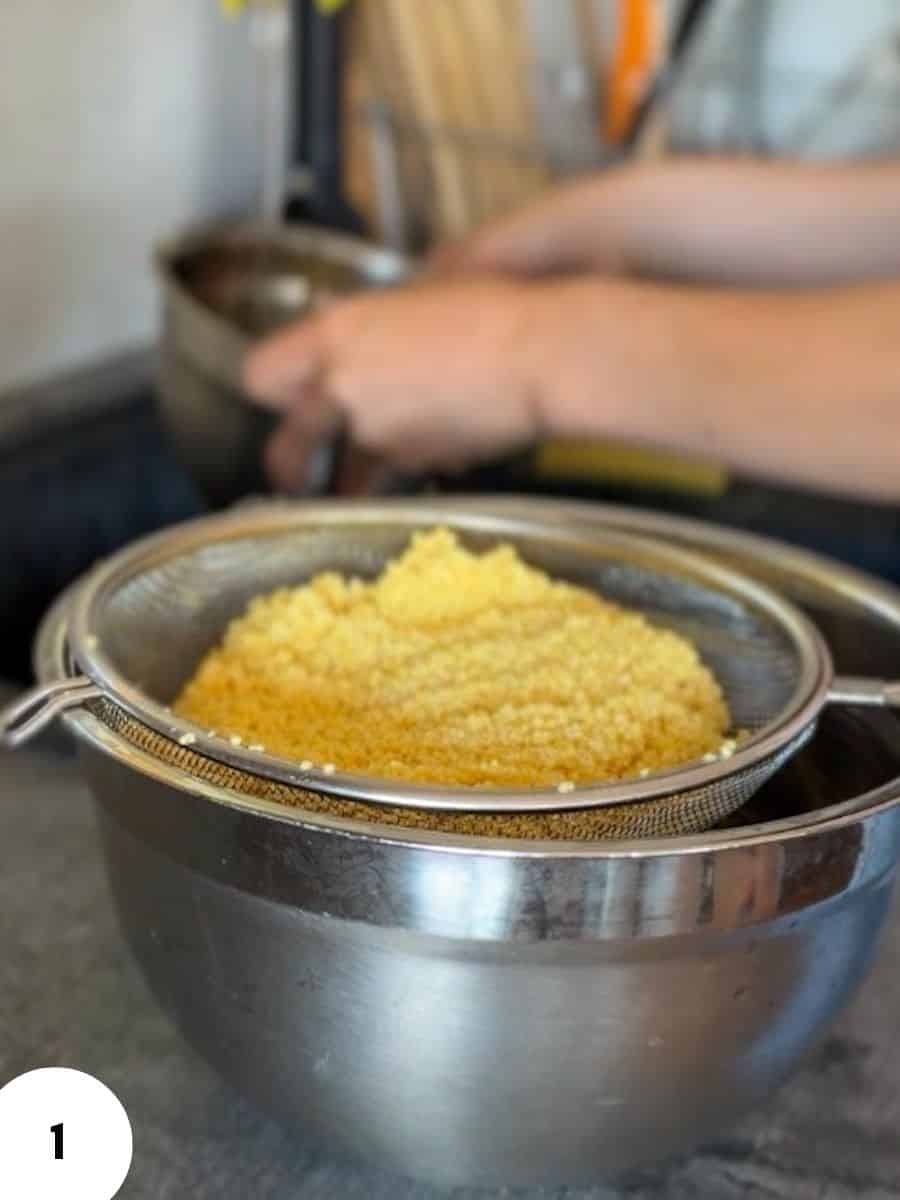 Close-up of dough being strained in a metal sieve over a mixing bowl.