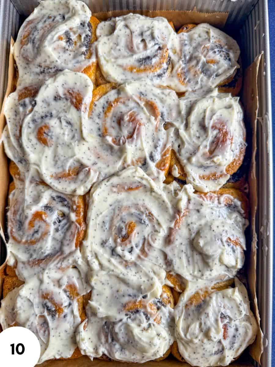 Close-up of cinnamon rolls with creamy icing in a baking tray.