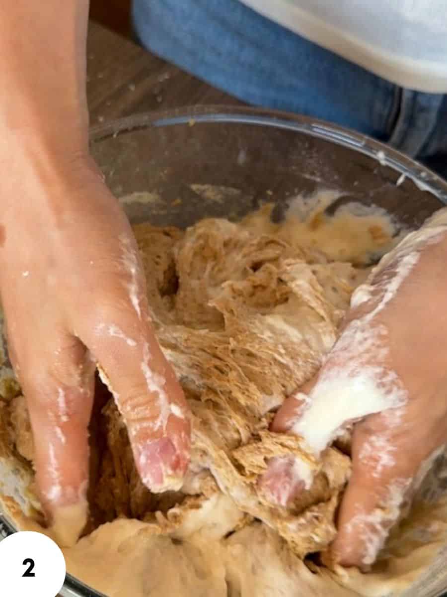 Hands performing stretch and fold technique on bread dough.