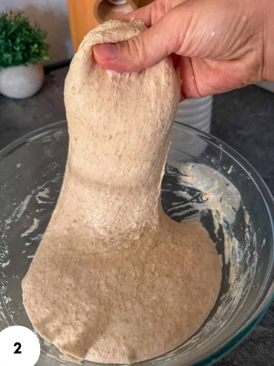 Dough being stretched and folded in a glass bowl for bread baking.