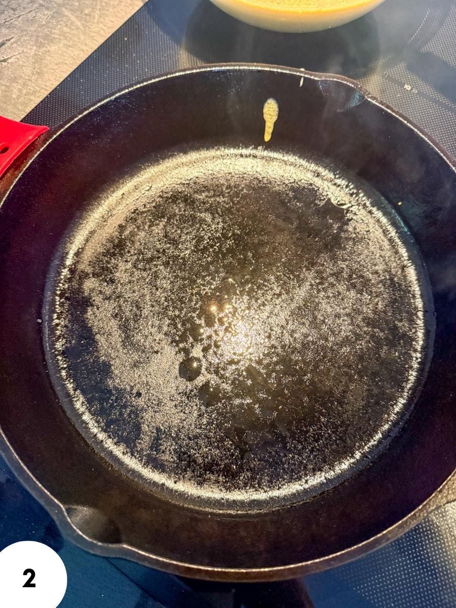 Empty cast iron skillet with oil residue for bread dough stretching.