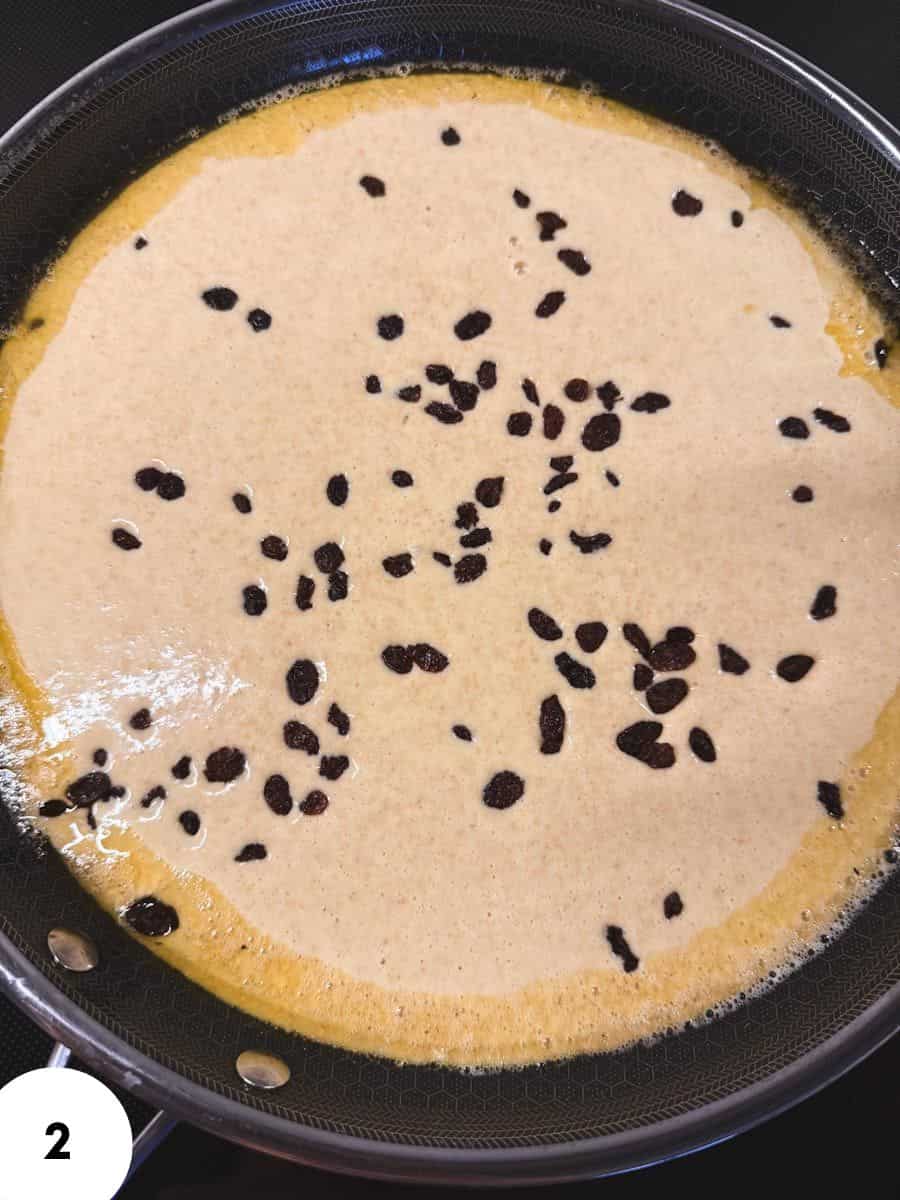 Close-up of a creamy black sesame dessert with black sesame seeds on top.