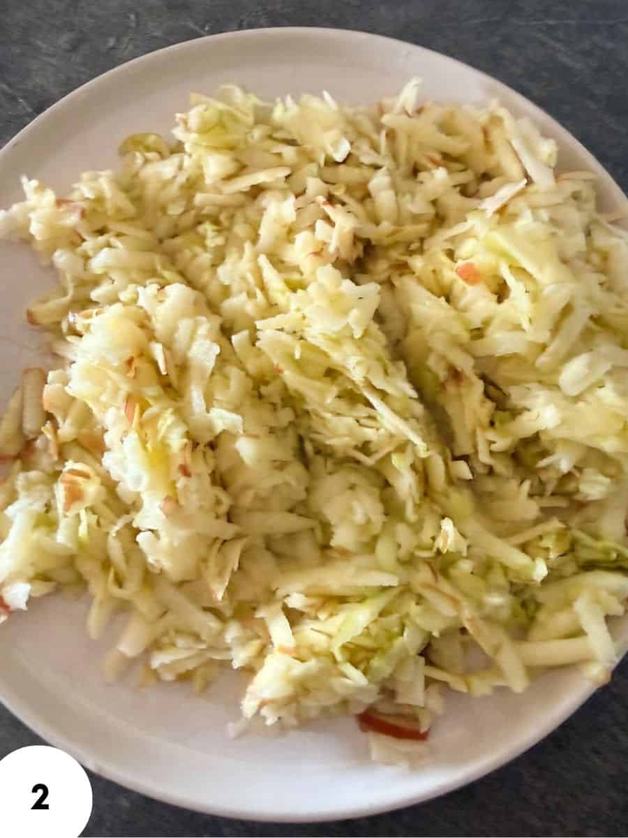 Close-up of shredded cabbage for sauerkraut on a white plate.