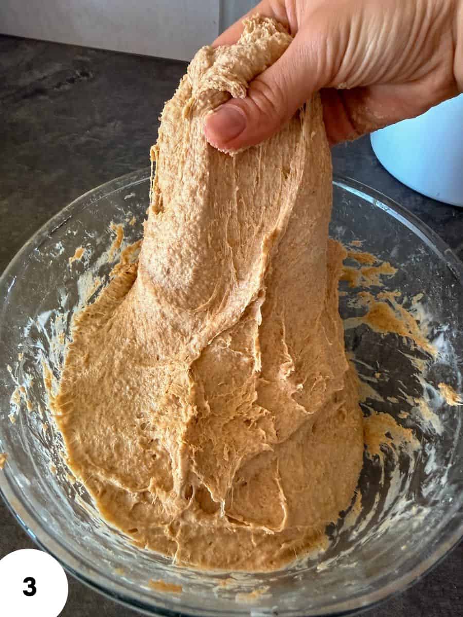 Hand performing stretch and fold dough for bread making.