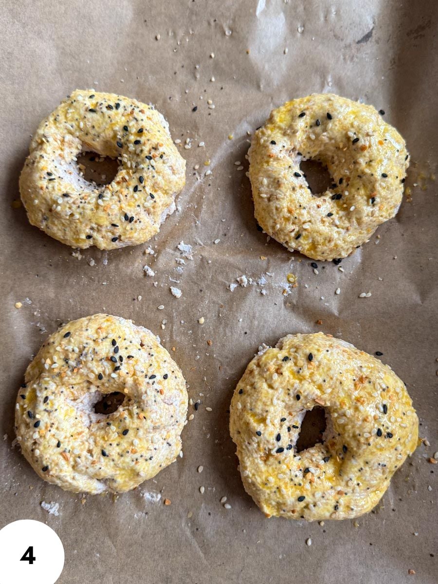 Freshly baked bagels with poppy and sesame seeds on parchment paper.