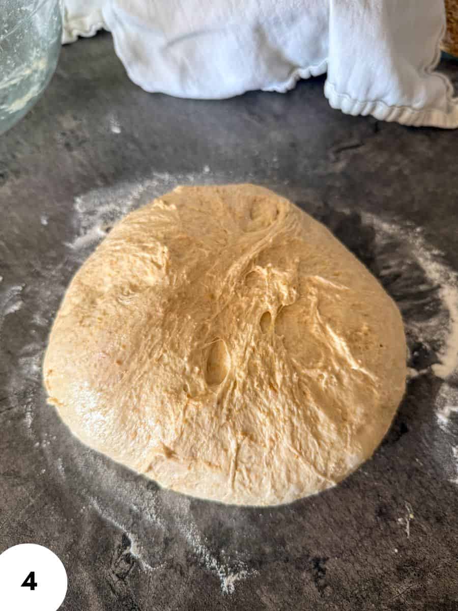 Dough ball prepared for stretch and folds on a floured surface.