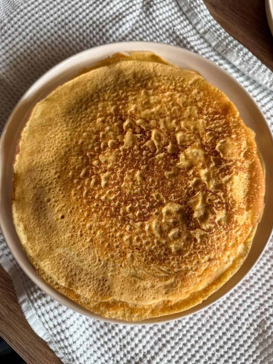 Close-up of a golden, crispy crepe on a white plate.