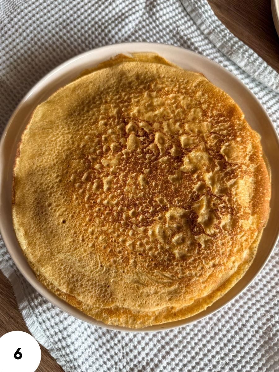 Golden brown crepe on a white plate, perfect for breakfast or dessert.